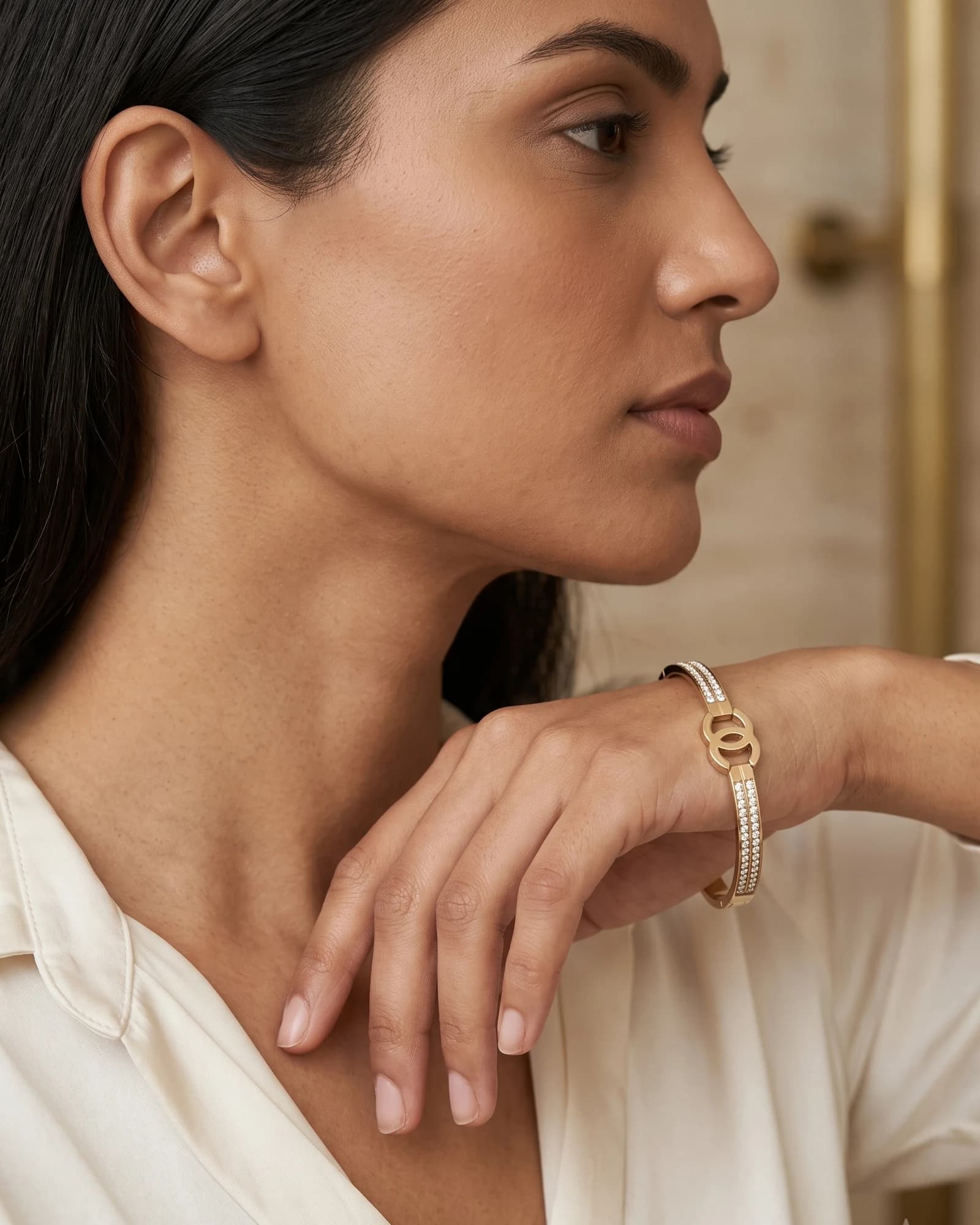 Model in an ivory silk shirt wearing a Krasna gold bangle — visualised campaign imagery