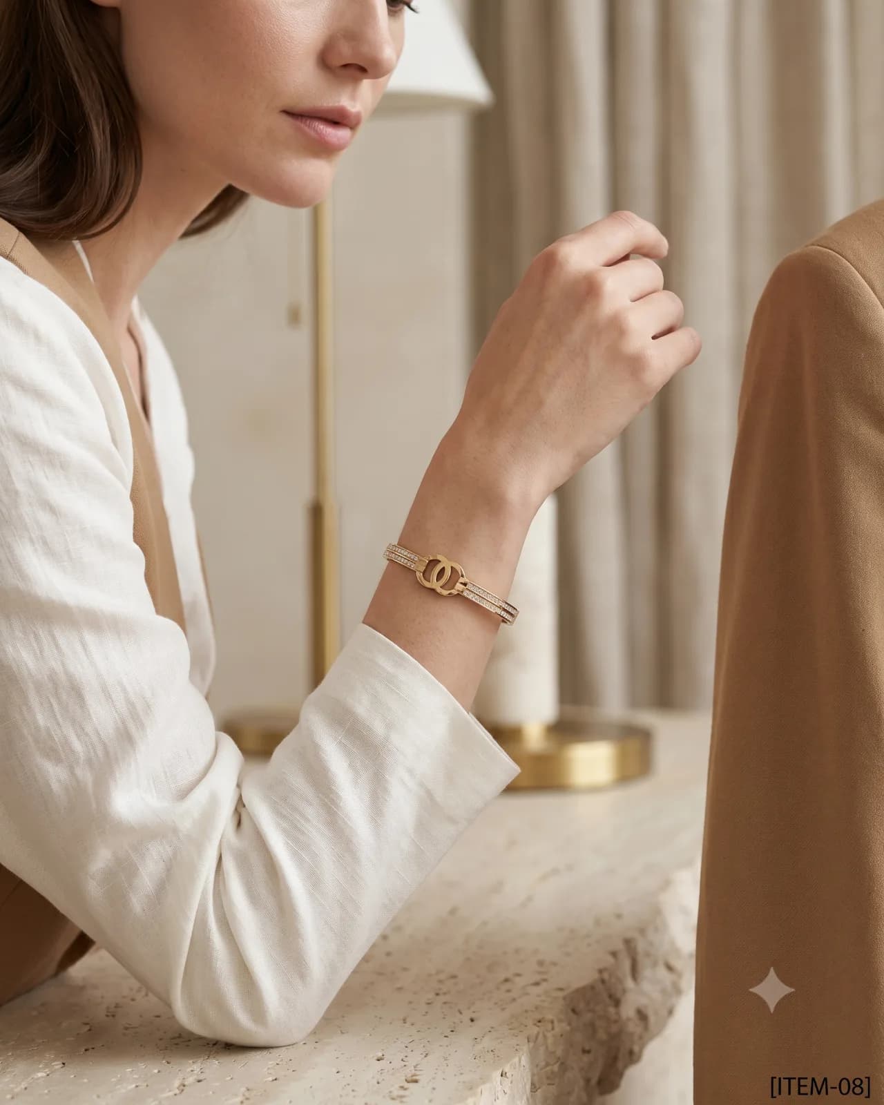 Aurelle Interlocked Bangle resting on a smooth, luxurious ivory silk