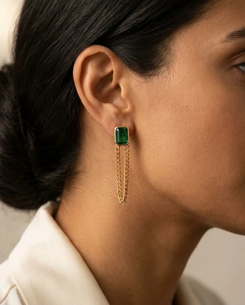 Front view of the Vana Emerald Chain earring with green stone and dangling curb chain